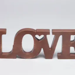 Letras de madera marrón forman la palabra "LOVE", con un corazón tallado en la "O".