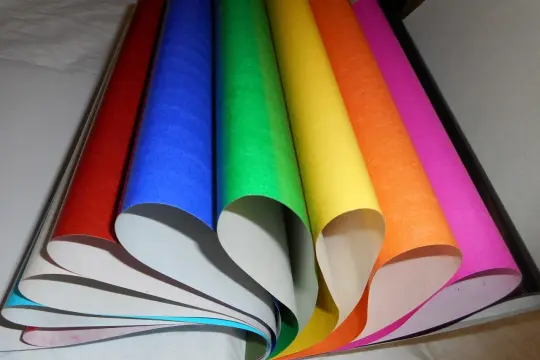 Rollos de papel charol de colores vibrantes, como un arcoíris desplegado, listos para dar vida a cualquier proyecto creativo.